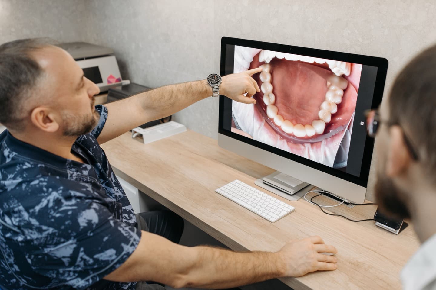 A dentist showing a patient a digital scan of their teeth on a screen during an exam