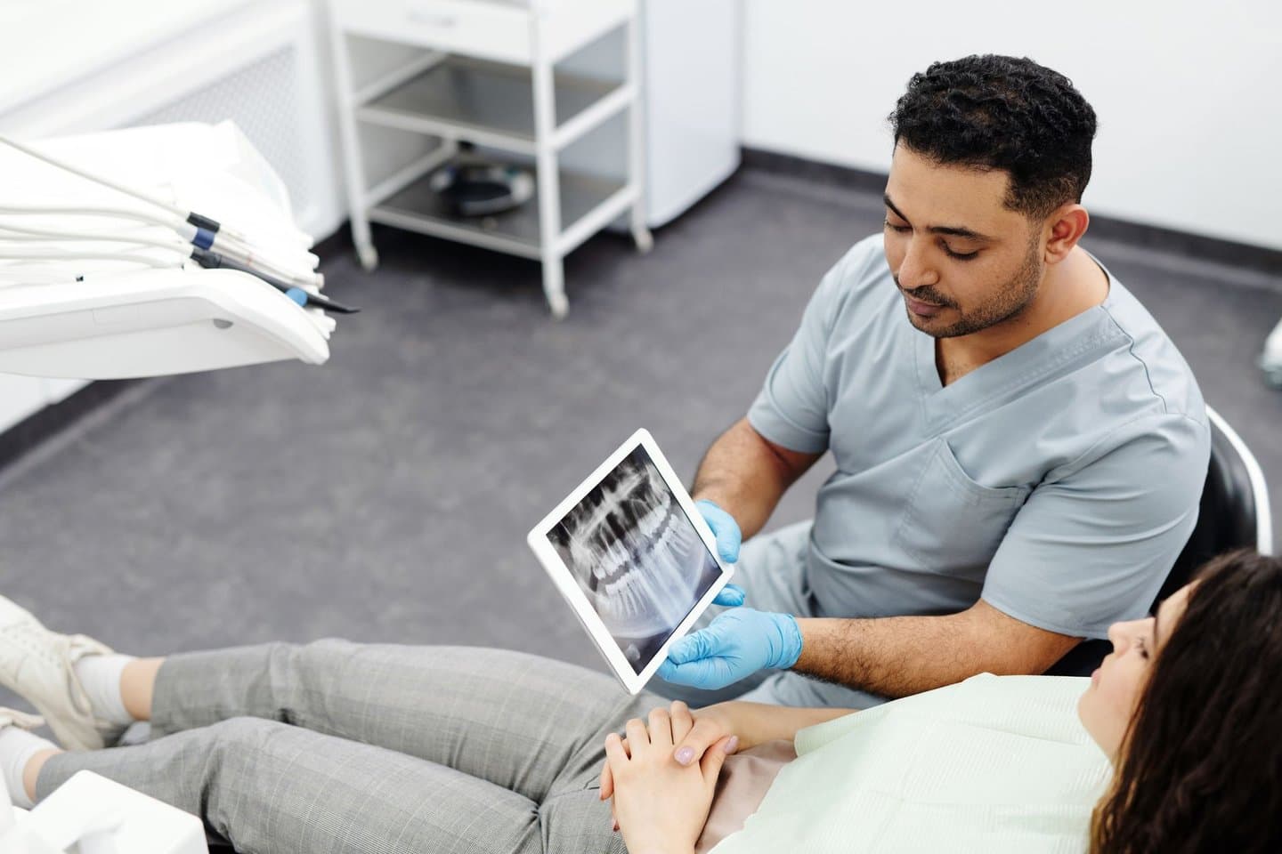 A dentist showing an X-ray image to a patient on a tablet