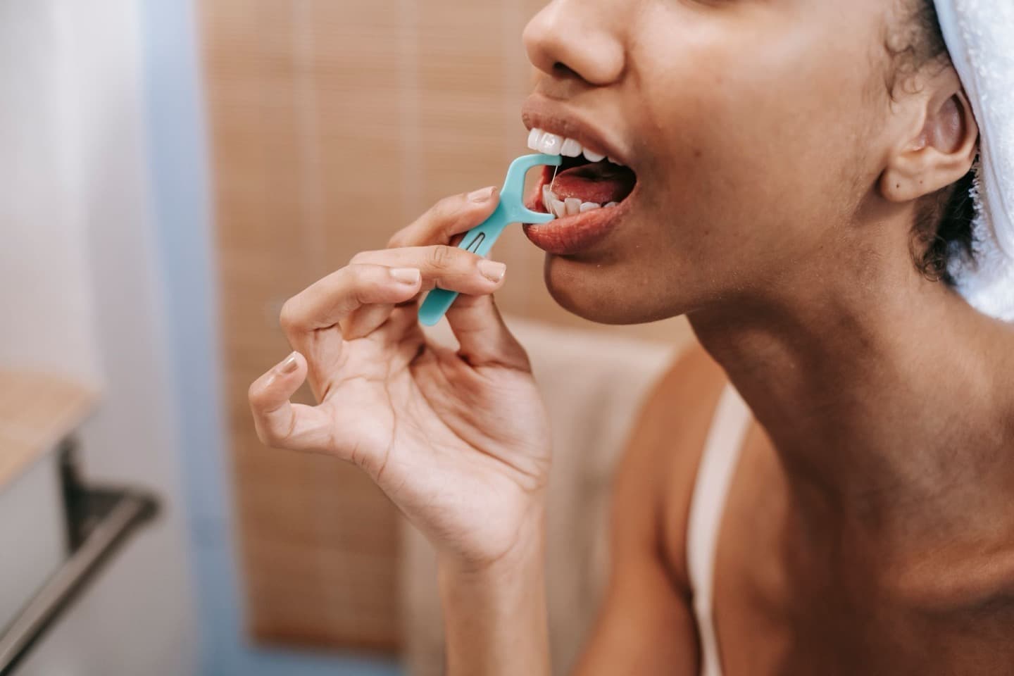A woman flossing her teeth at home