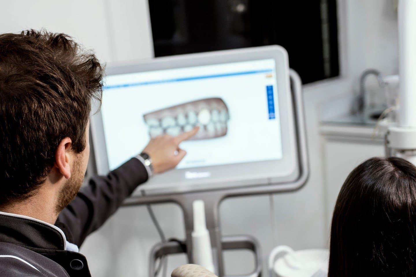 A dentist explaining a digital scan result to a patient on screen
