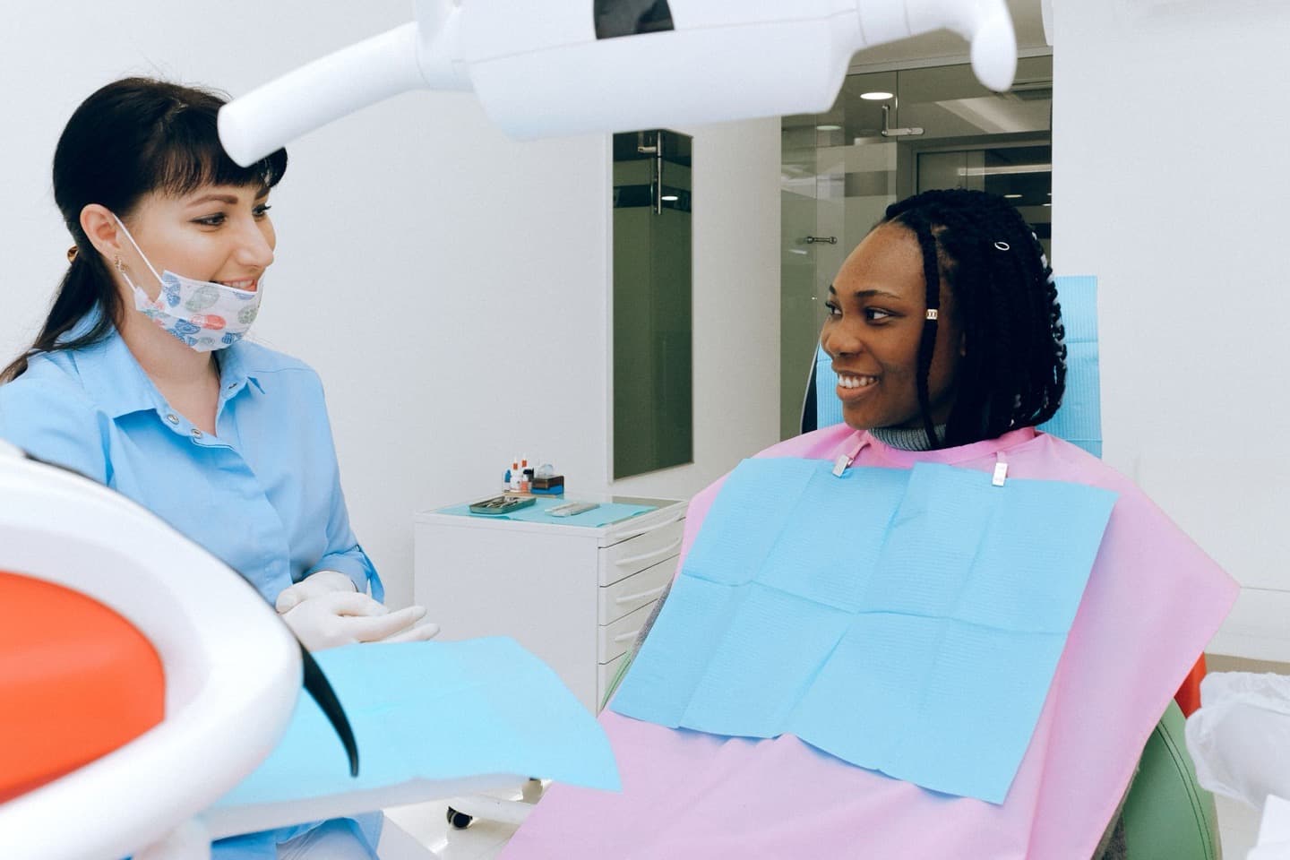 A dentist having a warm conversation with a patient seated in the dental chair